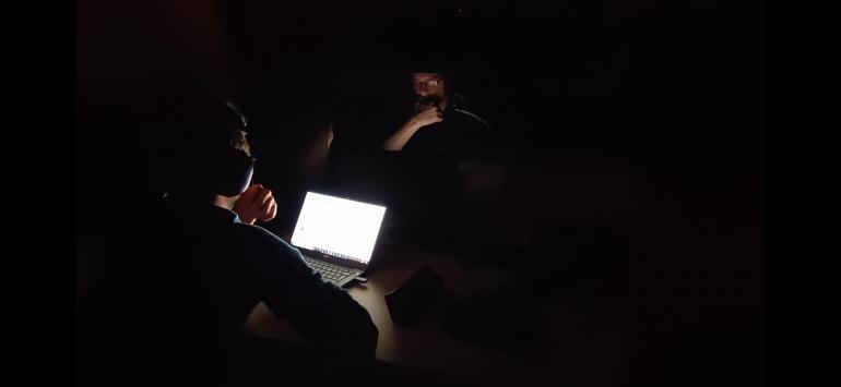 Programmers working on their laptop on a dark room.
